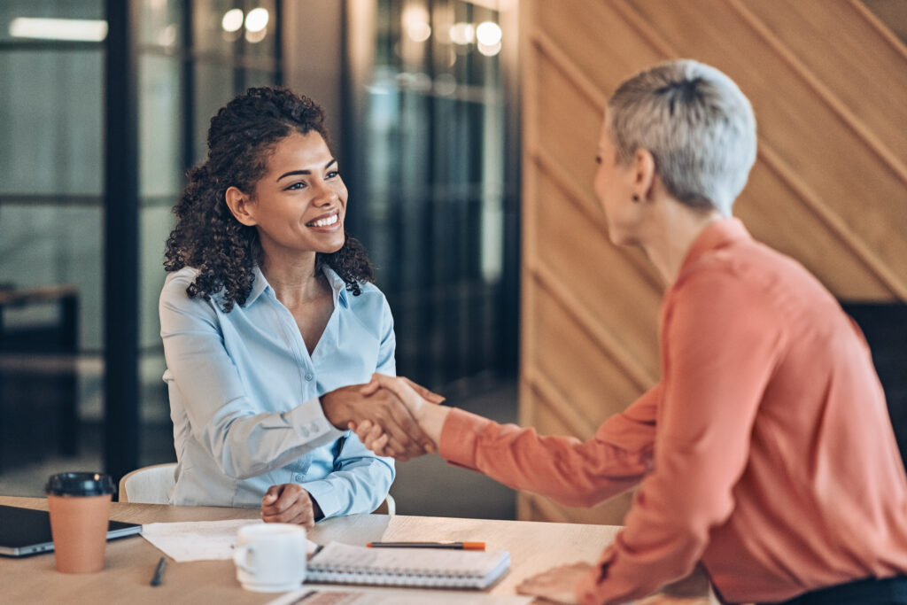 An OFX dealer shakes hands with a client at an in-person meeting.